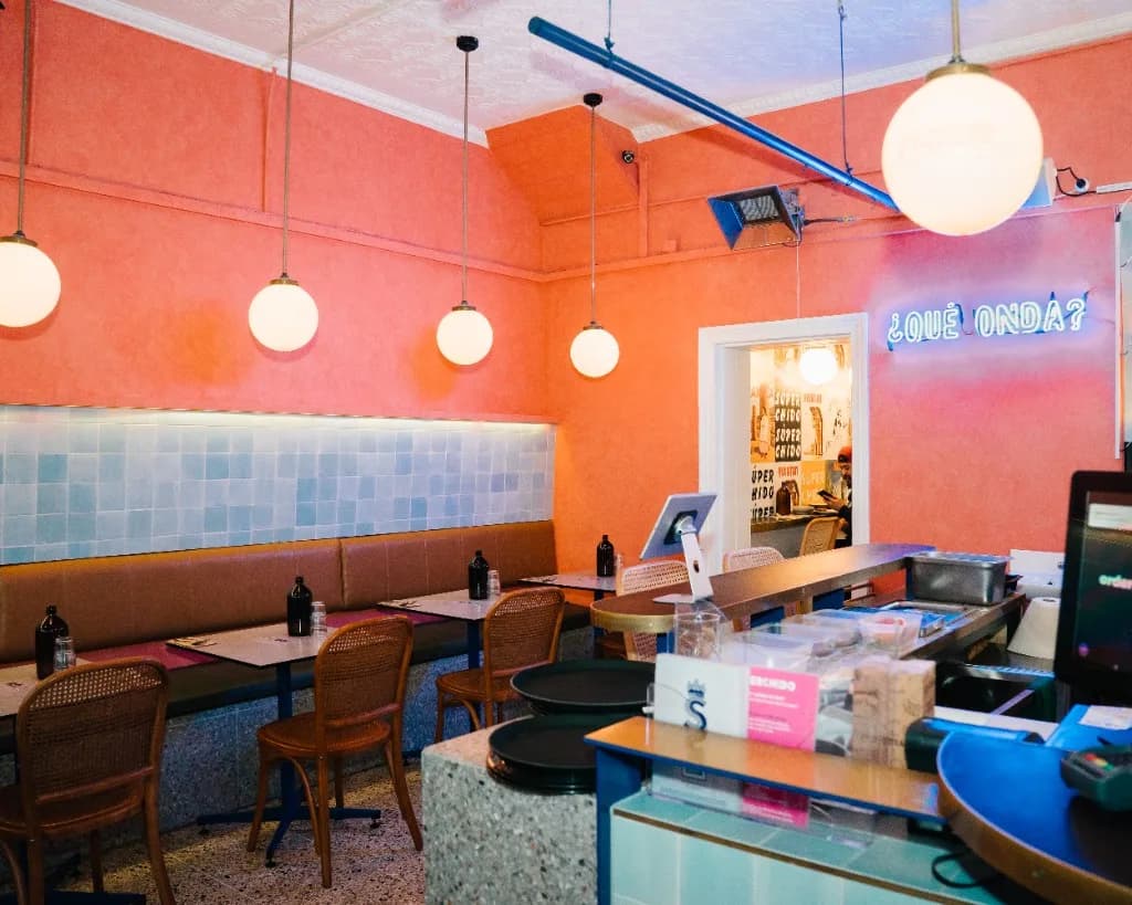 Superchido dining room with ¿Qué onda? neon sign and terrazzo bar