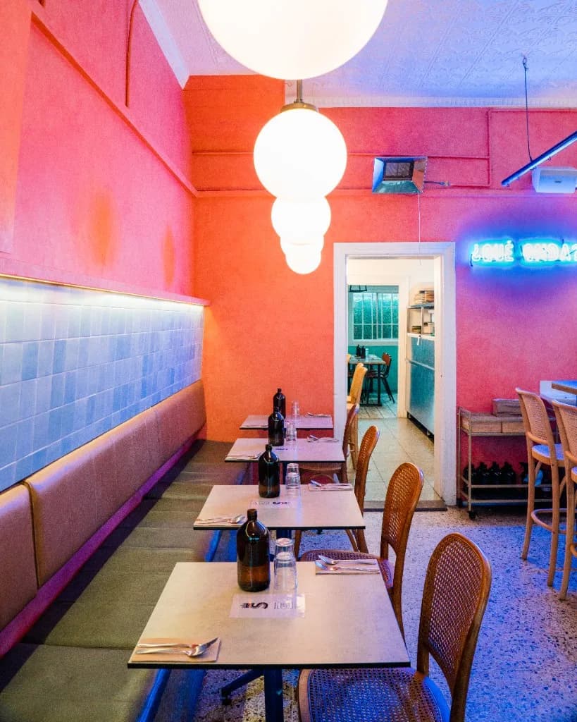 Pink dining room at Superchido with globe pendant lights and cane chairs